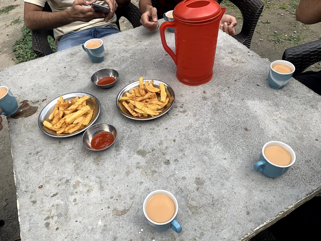 Cups of chai and fries on a table at a roadside dhaba