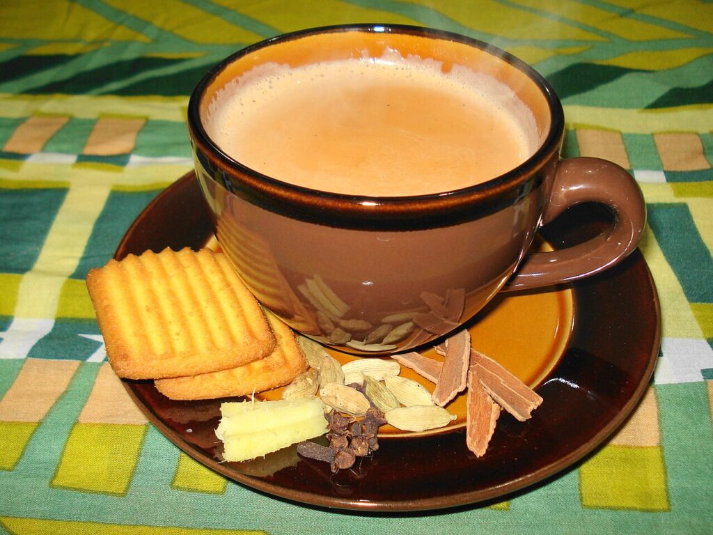 A cup of milky masala chai served with biscuits