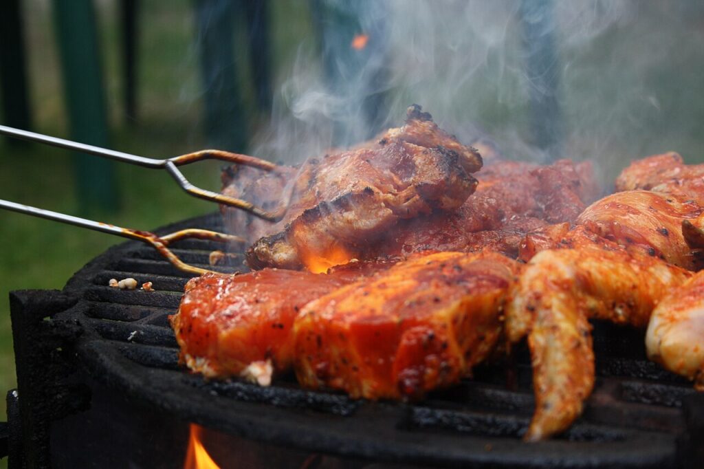 Steaks being turned with tongs on a grill
